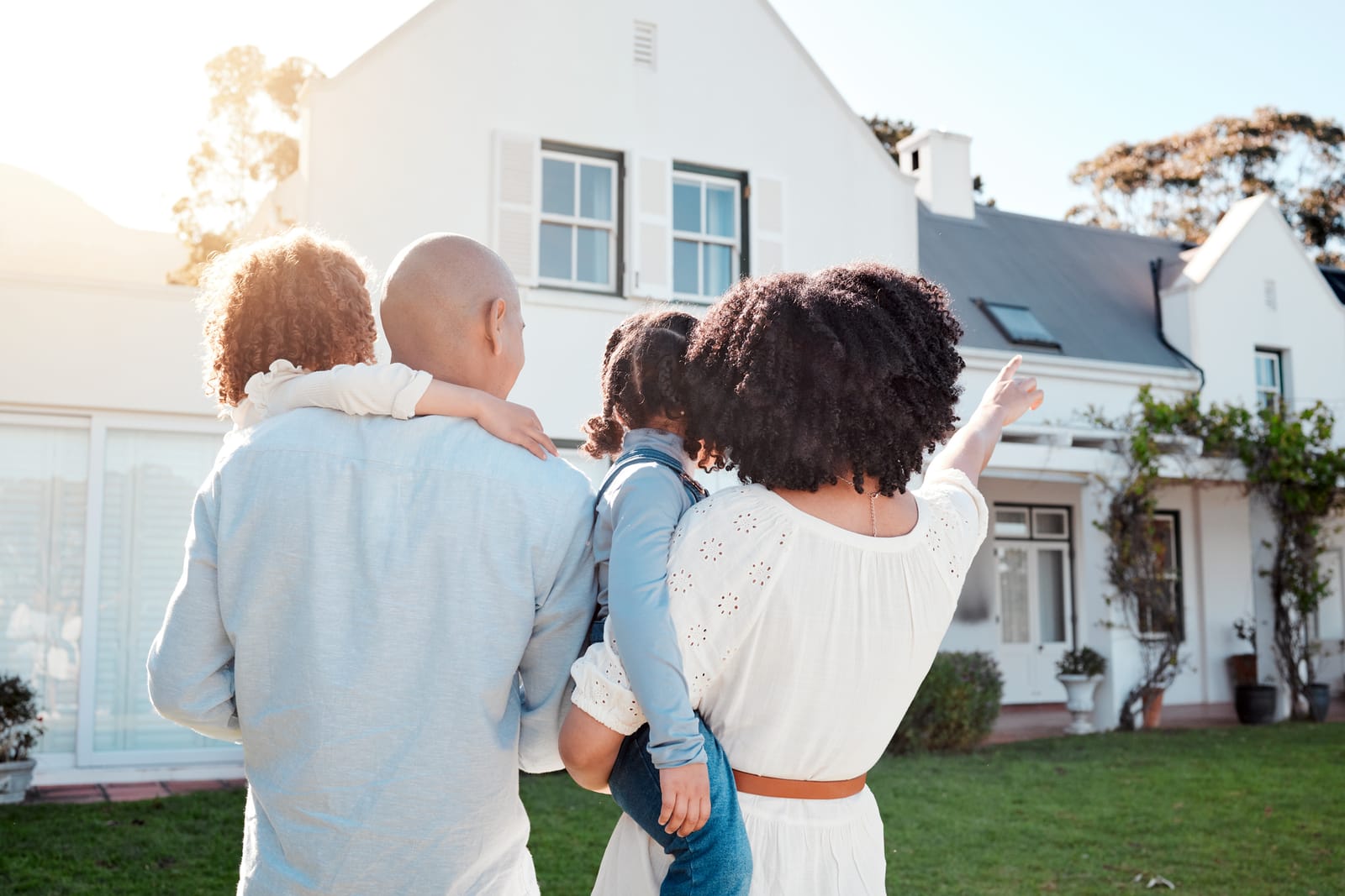 Happy family with parents and children playing in front of their home